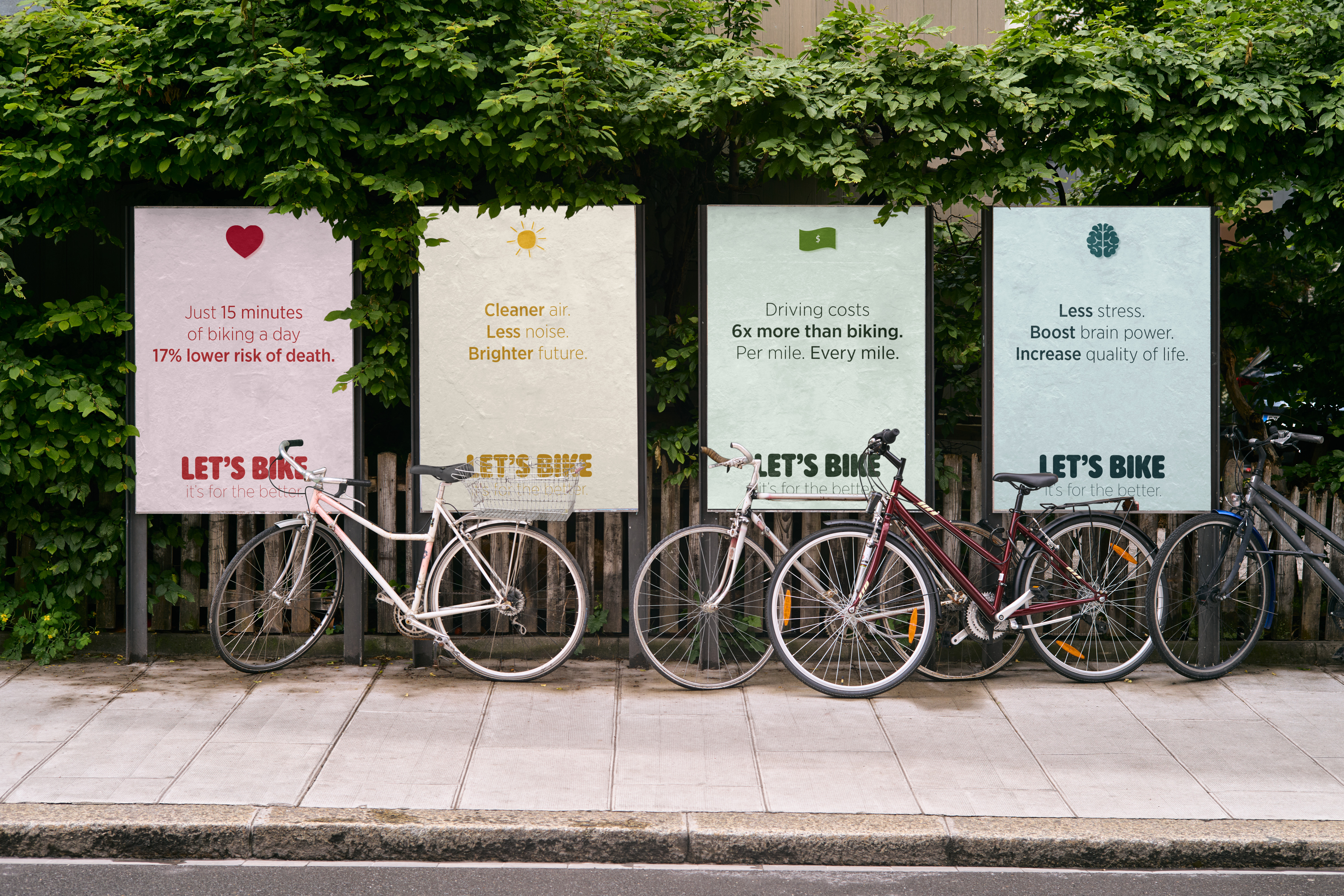 Let’s Bike campaign posters installed along a leafy city street.